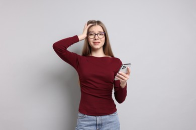 Photo of Teenage girl with smartphone on light grey background