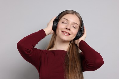 Photo of Teenage girl listening to music on light grey background