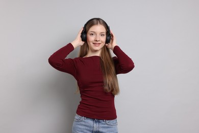 Photo of Teenage girl listening to music on light grey background