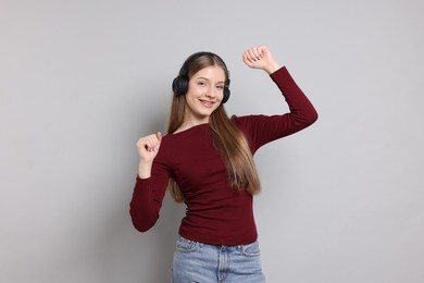 Photo of Teenage girl listening to music on light grey background