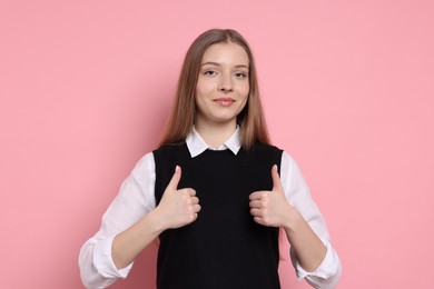 Photo of Teenage girl showing thumbs ups on light pink background