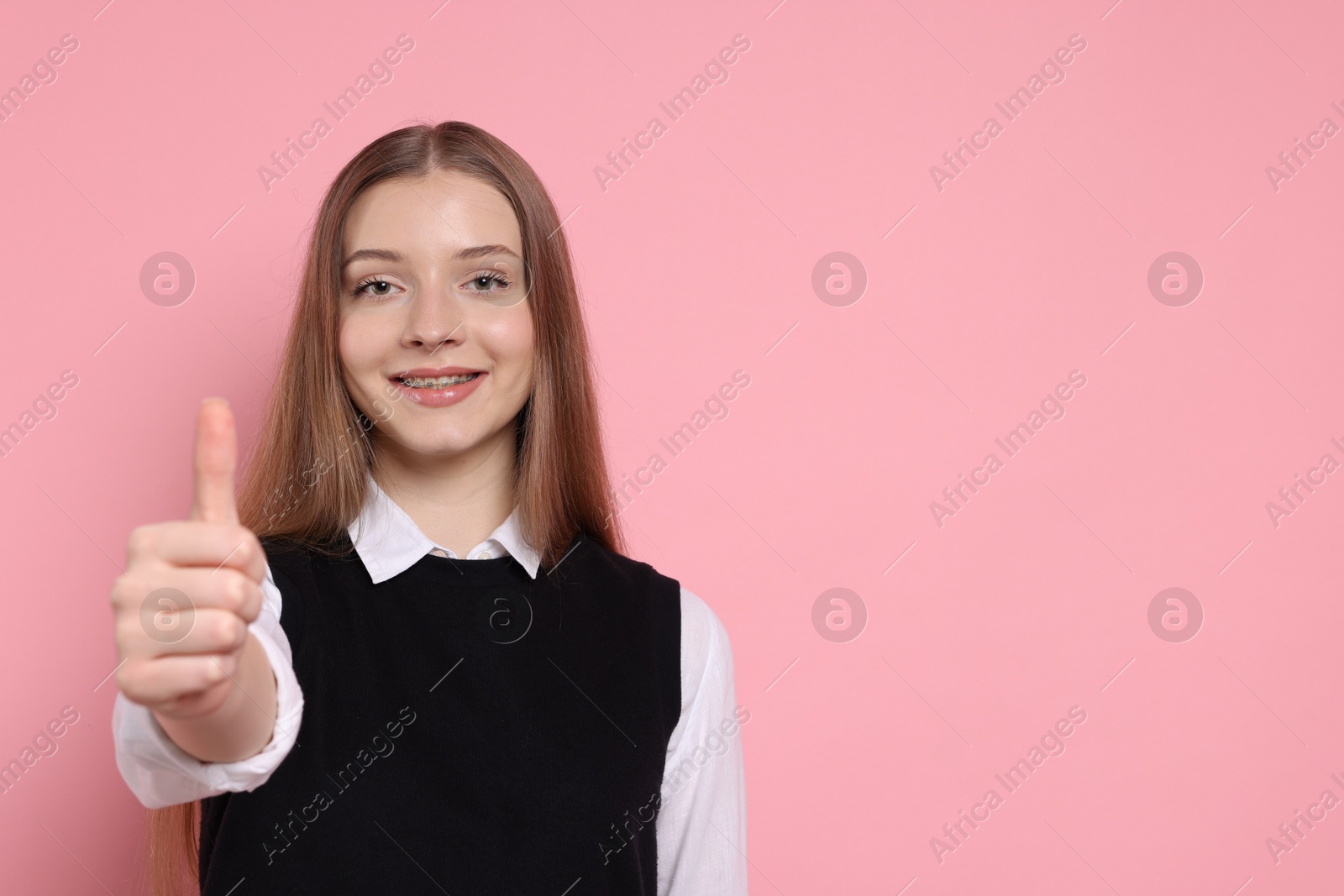 Teenage girl showing thumbs up on light pink background. Space for text Photo of Teenage girl showing thumbs up on light pink background. Space for text