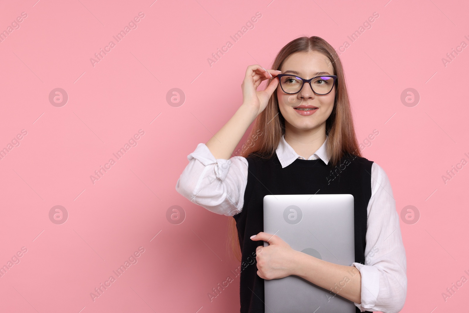 Photo of Beautiful teenage girl with laptop on pink background. Space for text