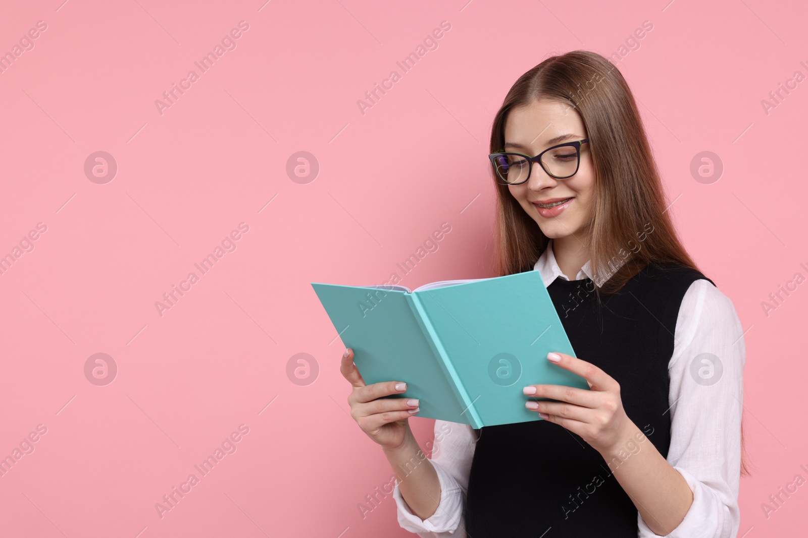 Photo of Teenage girl with book on light pink background. Space for text