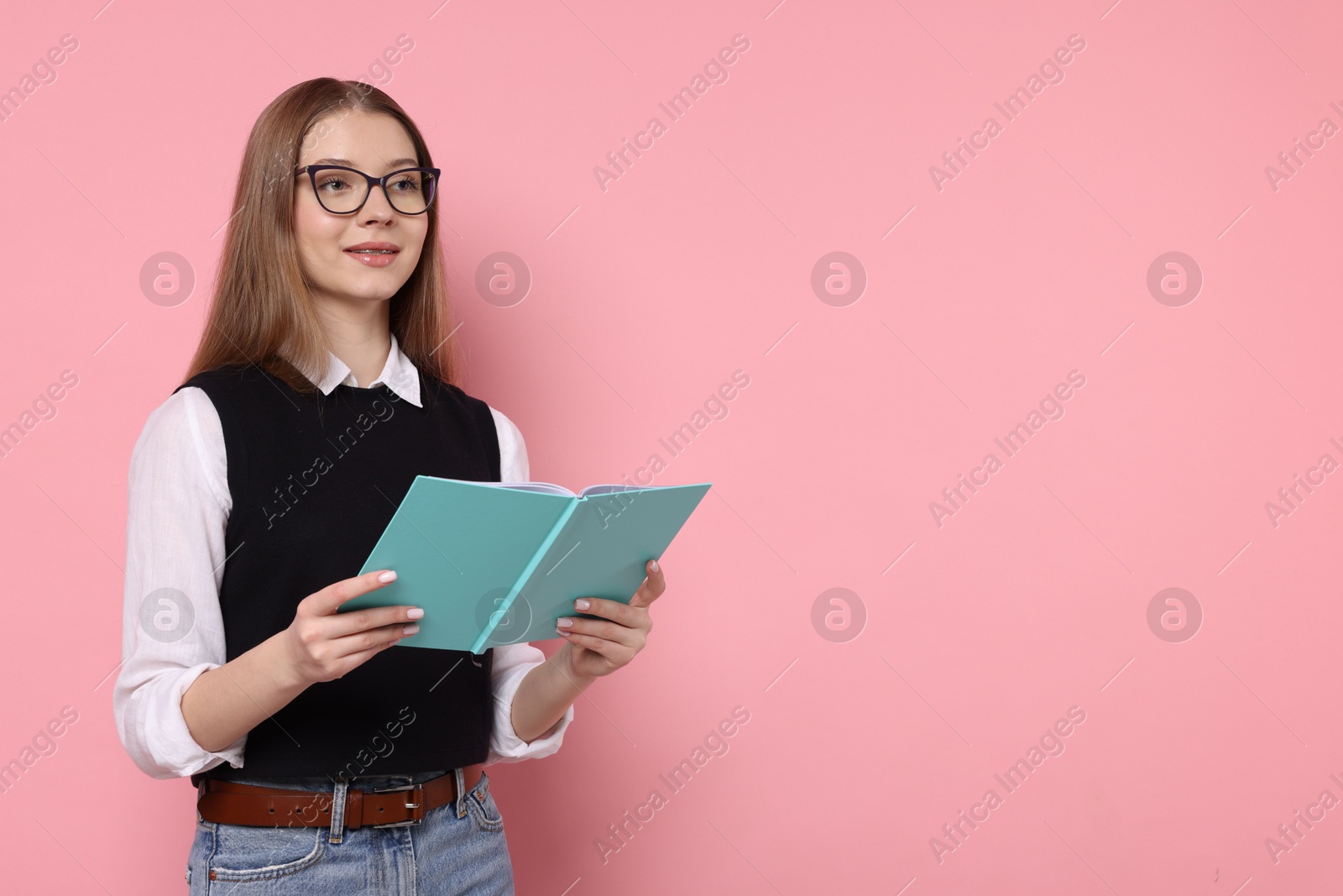 Photo of Teenage girl with book on light pink background. Space for text