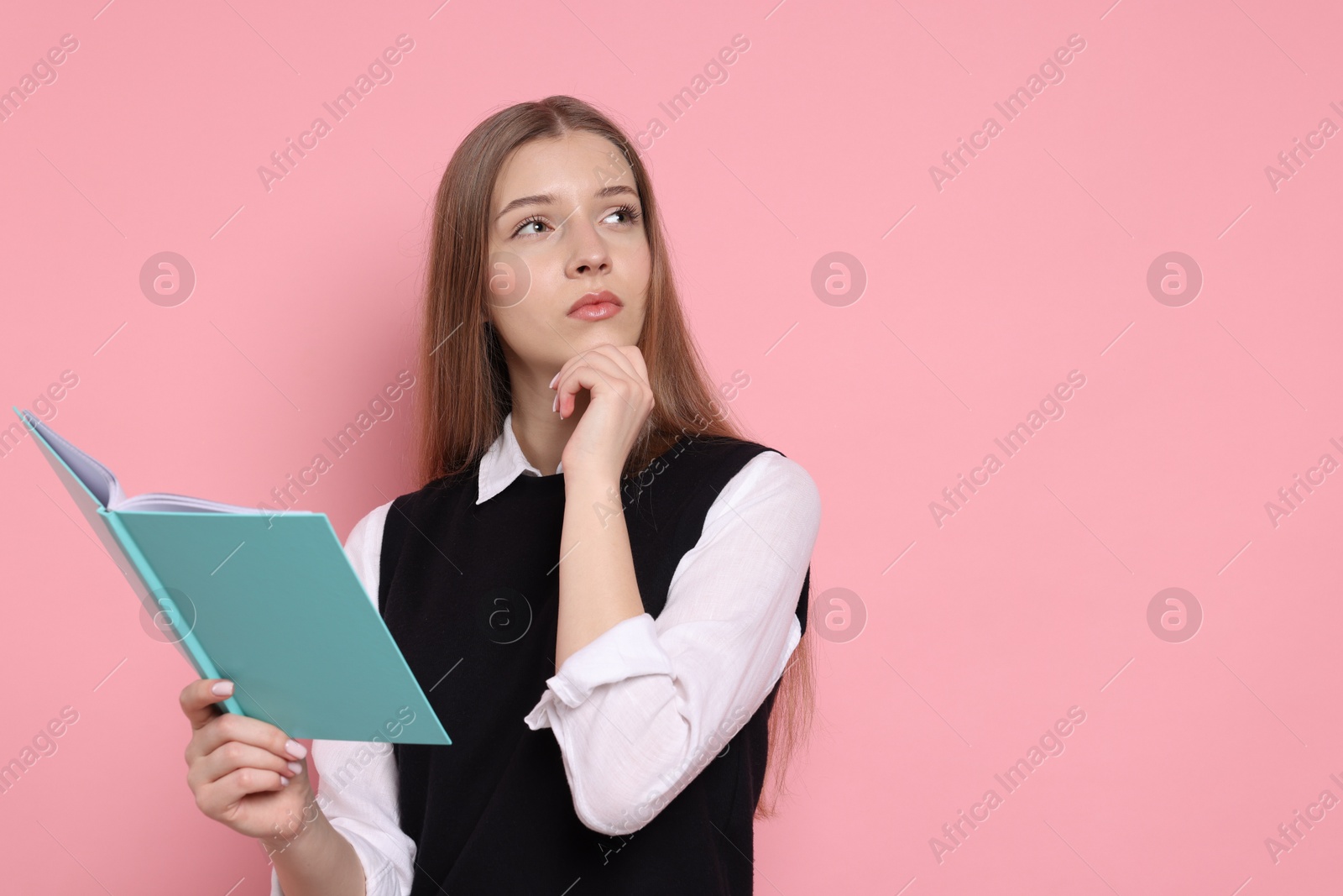 Photo of Pensive teenage girl with book on light pink background. Space for text