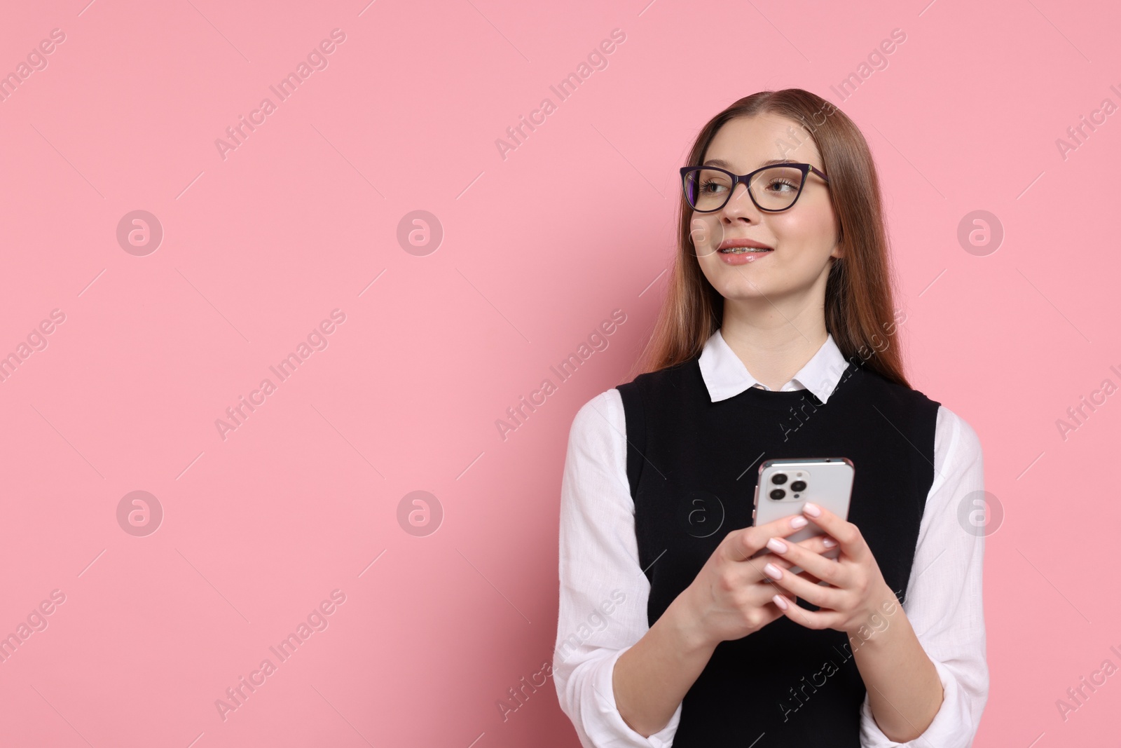 Photo of Teenage girl with smartphone on light pink background. Space for text