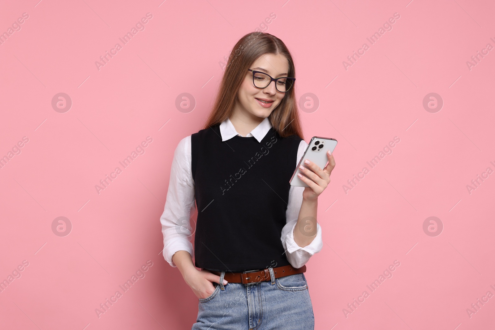 Photo of Teenage girl with smartphone on light pink background