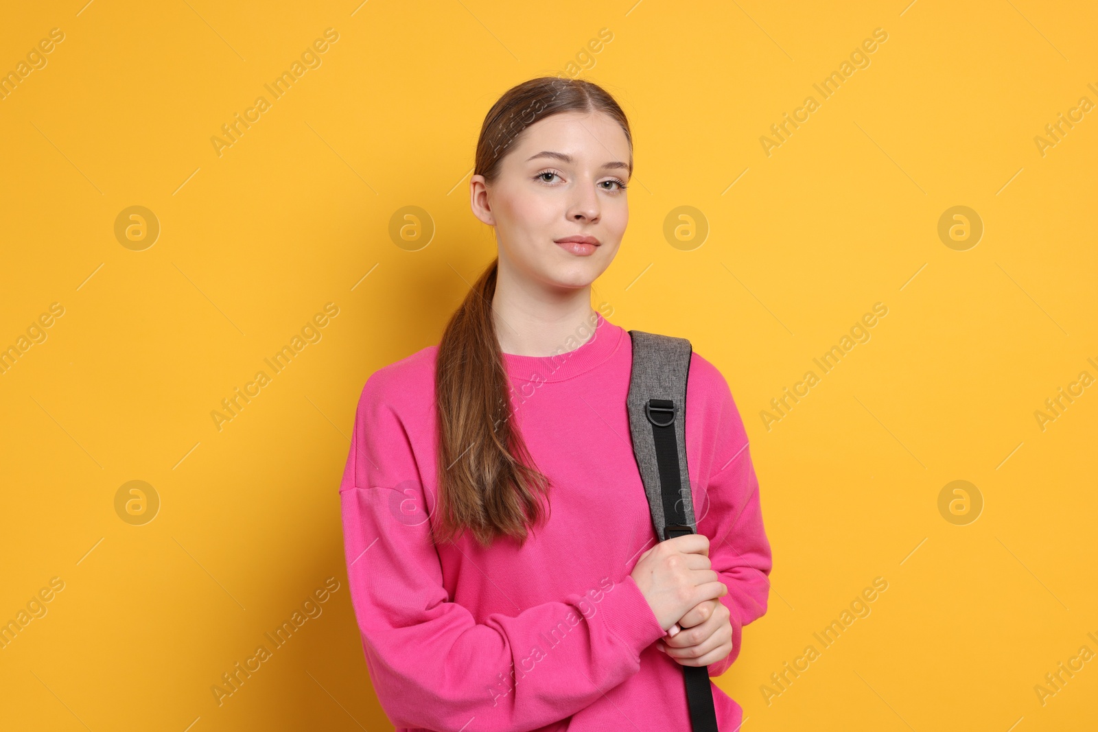 Photo of Teenage girl with backpack on yellow background
