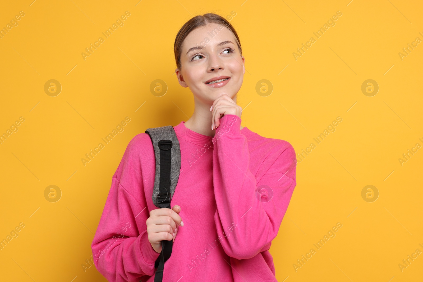 Photo of Teenage girl with backpack on yellow background