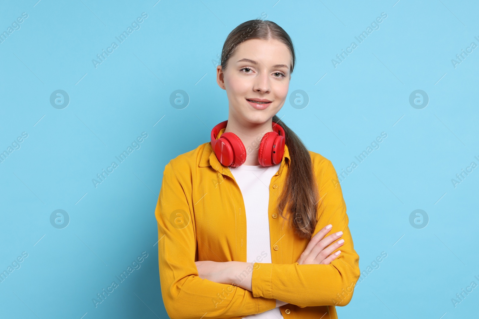 Photo of Teenage girl with headphones on light blue background