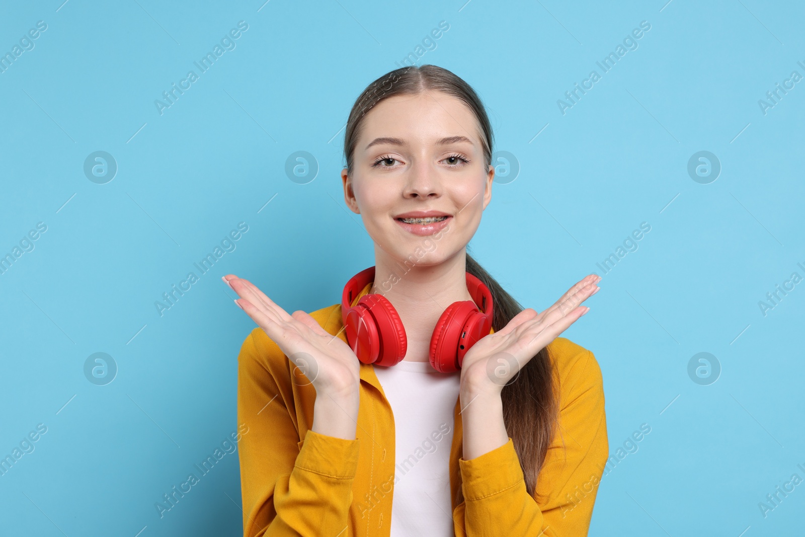 Photo of Teenage girl with headphones on light blue background