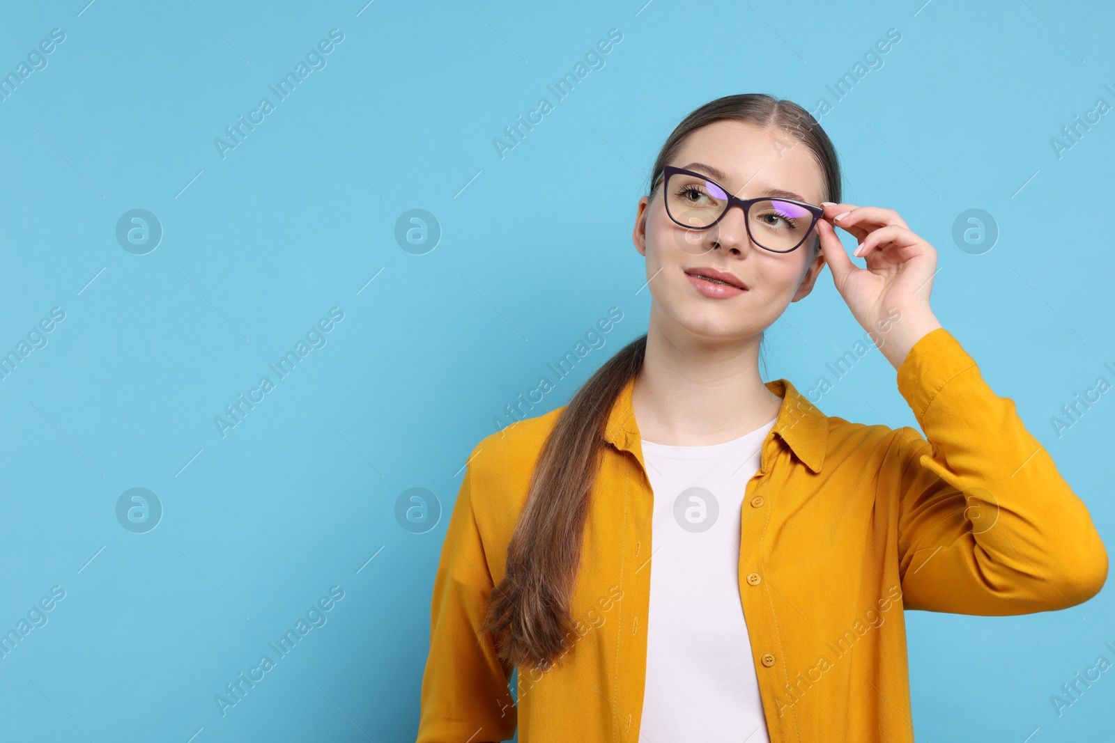 Photo of Portrait of teenage girl on light blue background. Space for text
