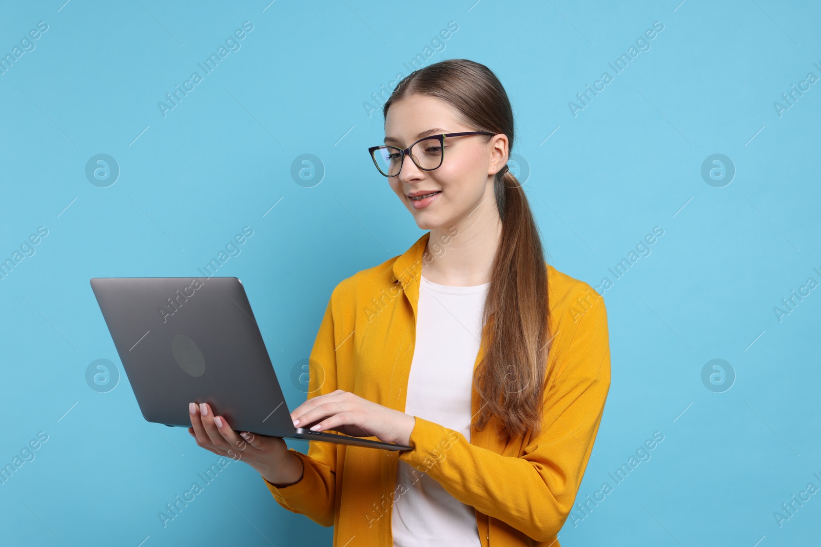 Photo of Teenage girl with laptop on light blue background