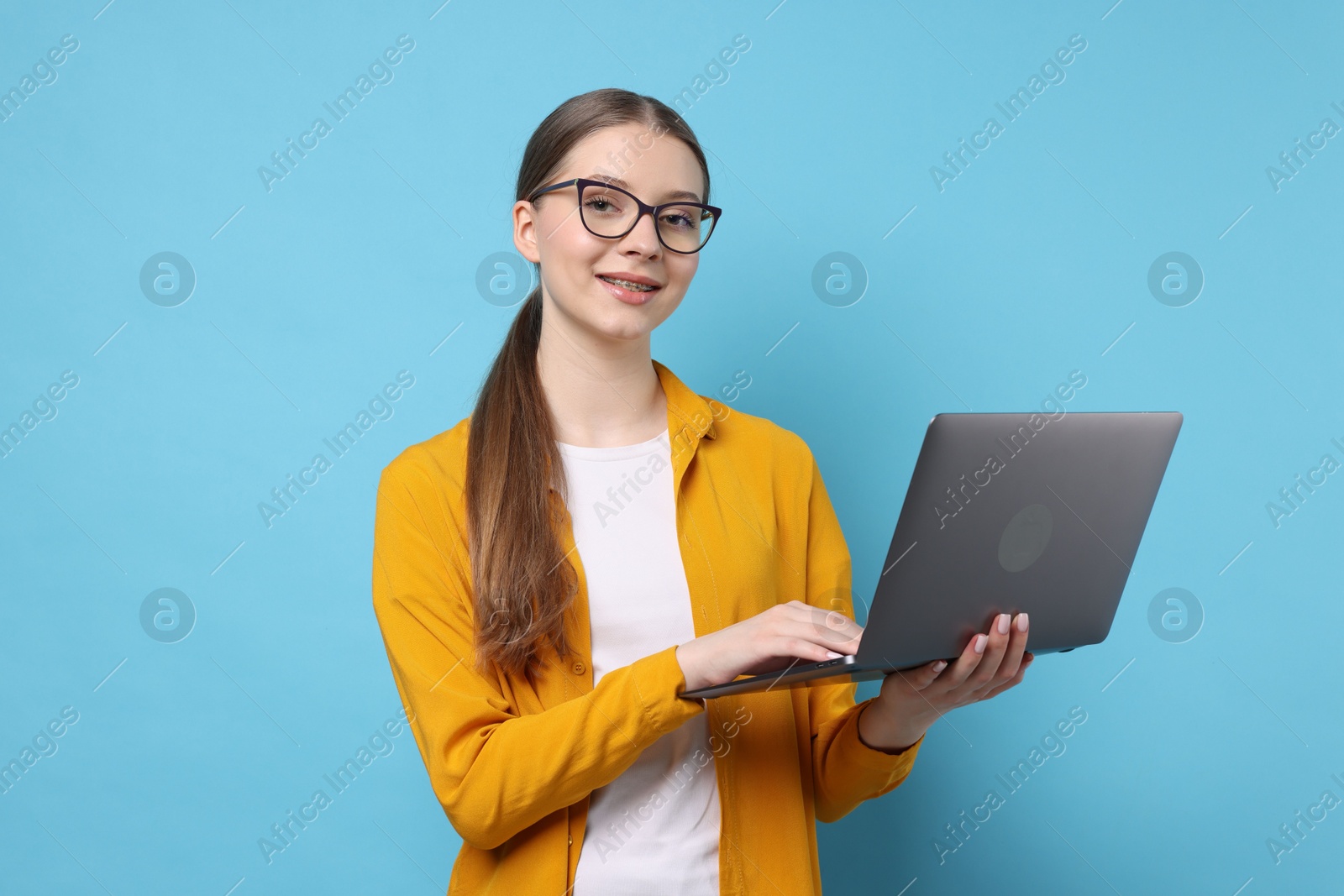 Photo of Teenage girl with laptop on light blue background