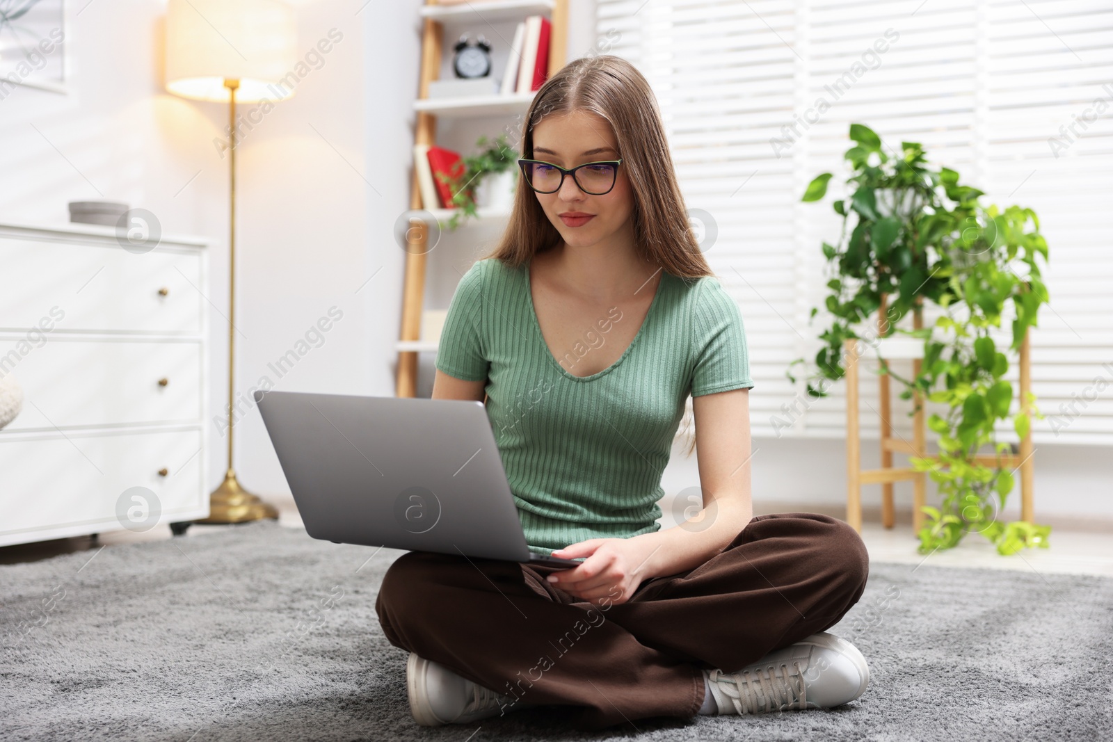 Teenage girl with laptop on floor at home Photo of Teenage girl with laptop on floor at home