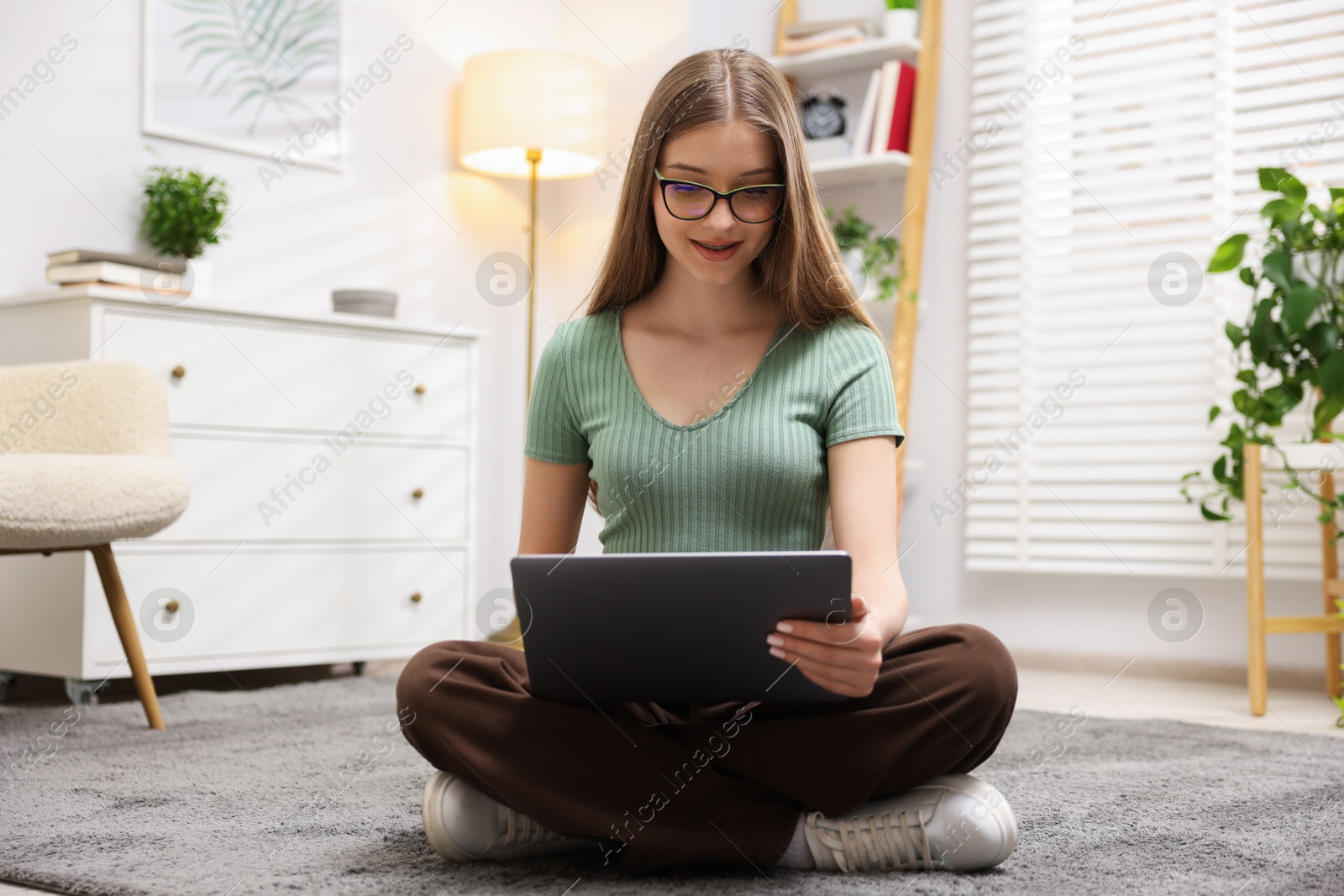 Teenage girl with laptop on floor at home Photo of Teenage girl with laptop on floor at home
