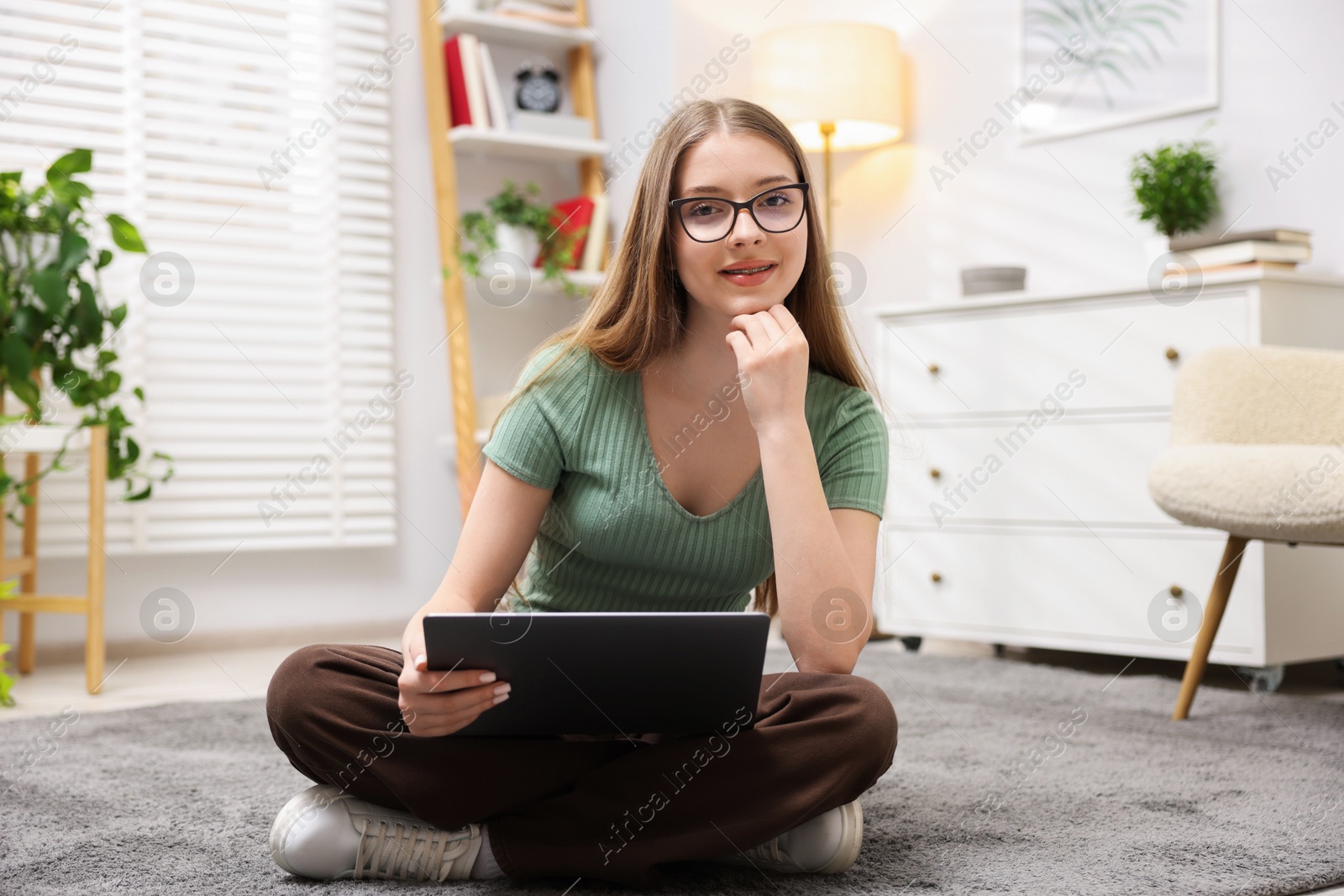 Teenage girl with laptop on floor at home Photo of Teenage girl with laptop on floor at home