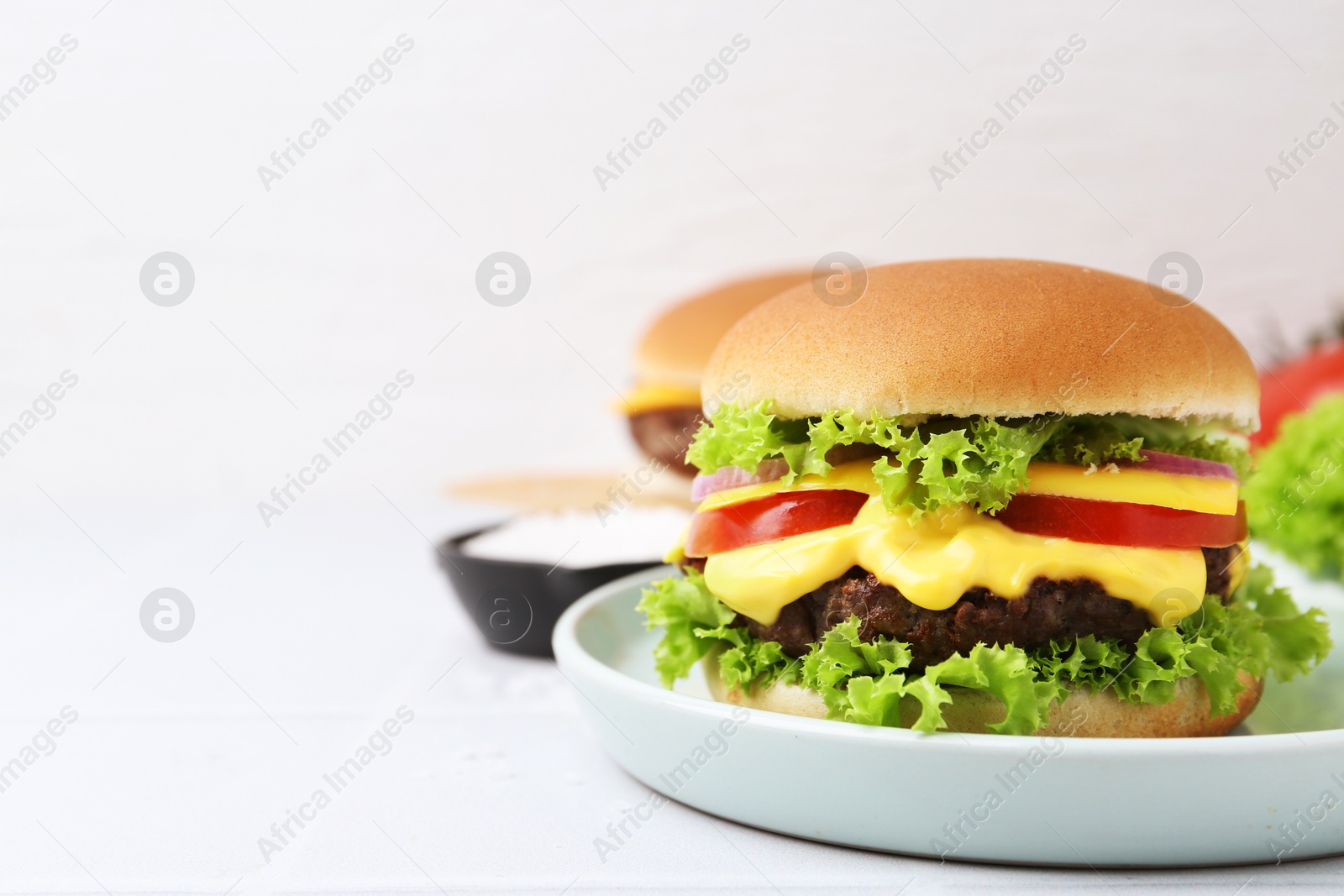 Tasty cheeseburger on white table, closeup. Space for text Photo of Tasty cheeseburger on white table, closeup. Space for text