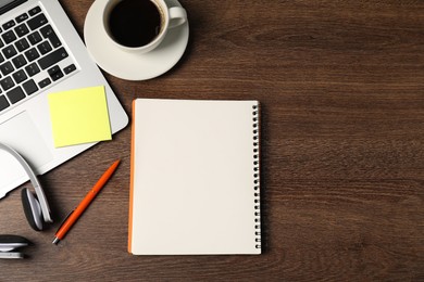 Photo of Notebook, sticky note, pen, headphones, coffee and laptop on wooden table, flat lay. Space for text