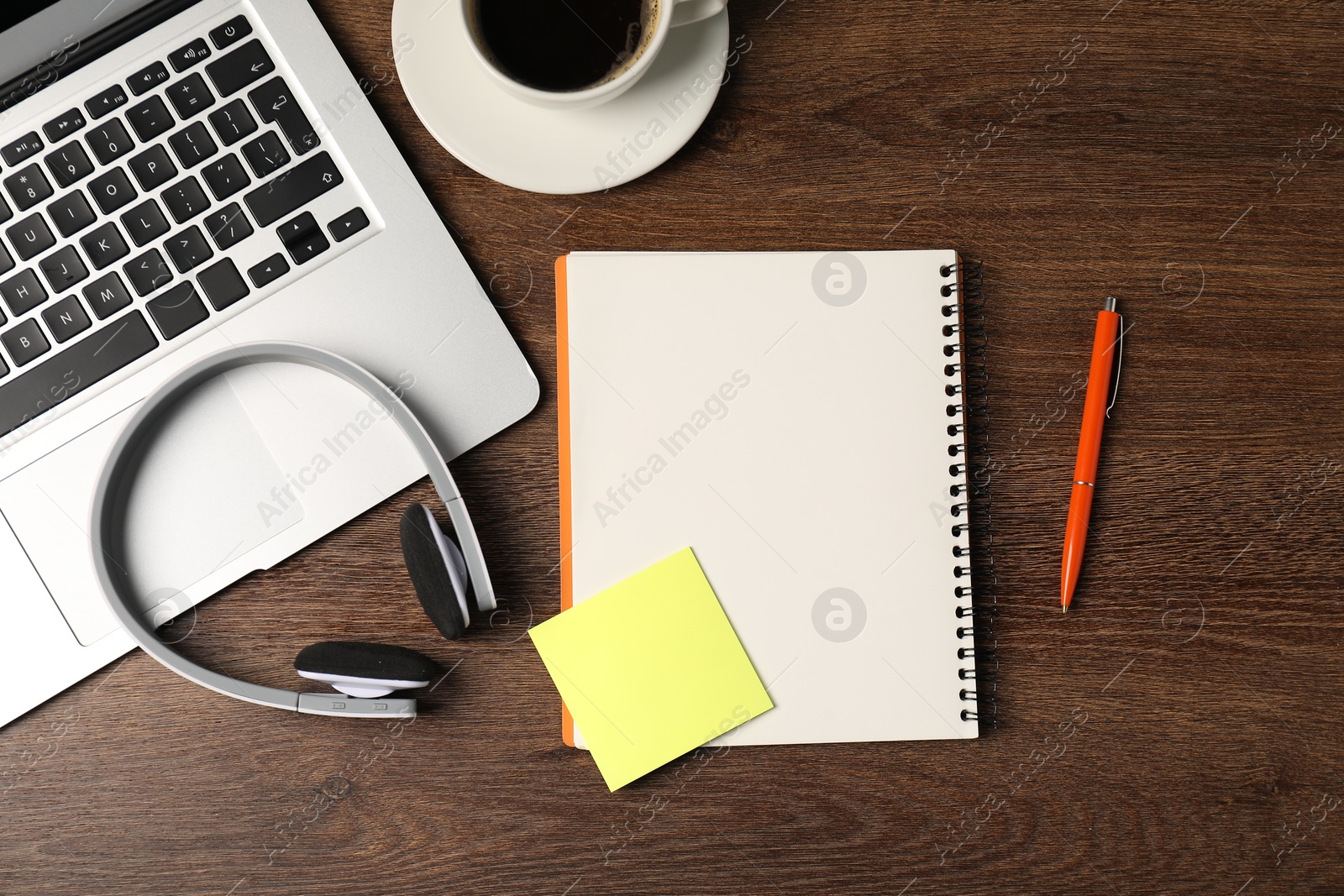 Notebook, sticky note, pen, headphones, coffee and laptop on wooden table, flat lay Photo of Notebook, sticky note, pen, headphones, coffee and laptop on wooden table, flat lay