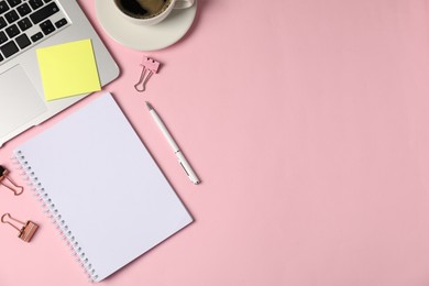 Photo of Notebook, sticky note, pen, binder clips, coffee and laptop on pink background, flat lay. Space for text