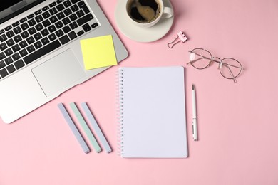 Photo of Notebook, sticky note, pen, markers, binder clip, coffee and laptop on pink background, flat lay