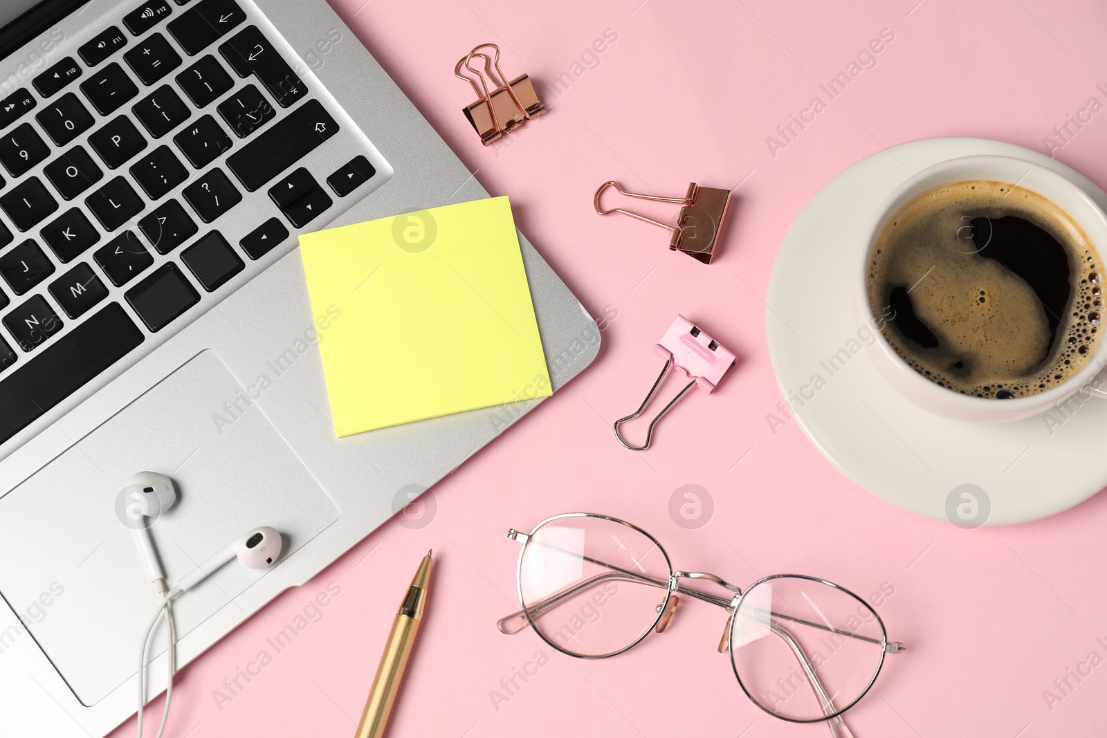 Sticky note, pen, binder clips, glasses, coffee, earphones and laptop on pink background, flat lay Photo of Sticky note, pen, binder clips, glasses, coffee, earphones and laptop on pink background, flat lay