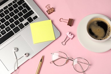 Photo of Sticky note, pen, binder clips, glasses, coffee, earphones and laptop on pink background, flat lay