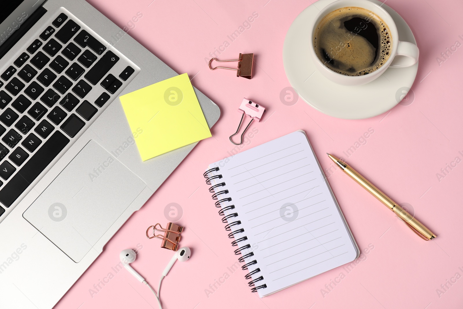 Notebook, sticky note, pen, binder clips, coffee, earphones and laptop on pink background, flat lay Photo of Notebook, sticky note, pen, binder clips, coffee, earphones and laptop on pink background, flat lay