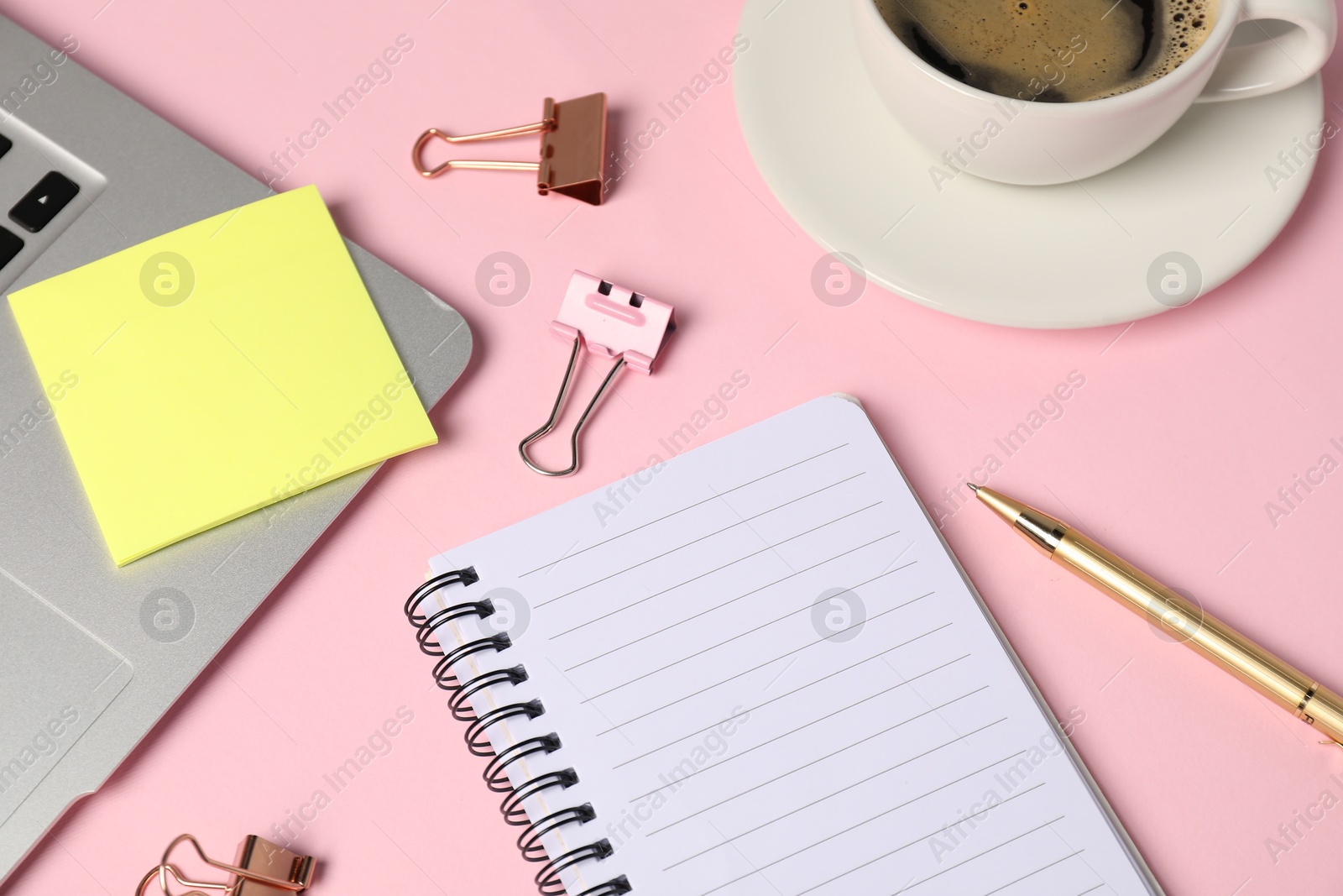 Notebook, sticky note, pen, binder clips, coffee and laptop on pink background, above view Photo of Notebook, sticky note, pen, binder clips, coffee and laptop on pink background, above view