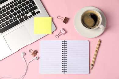 Photo of Notebook, sticky note, pen, binder clips, coffee, earphones and laptop on pink background, flat lay