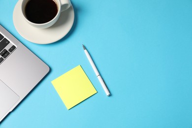 Photo of Sticky note, pen, coffee and laptop on light blue background, flat lay. Space for text