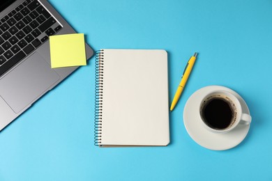 Photo of Notebook, sticky note, pen, coffee and laptop on light blue background, flat lay