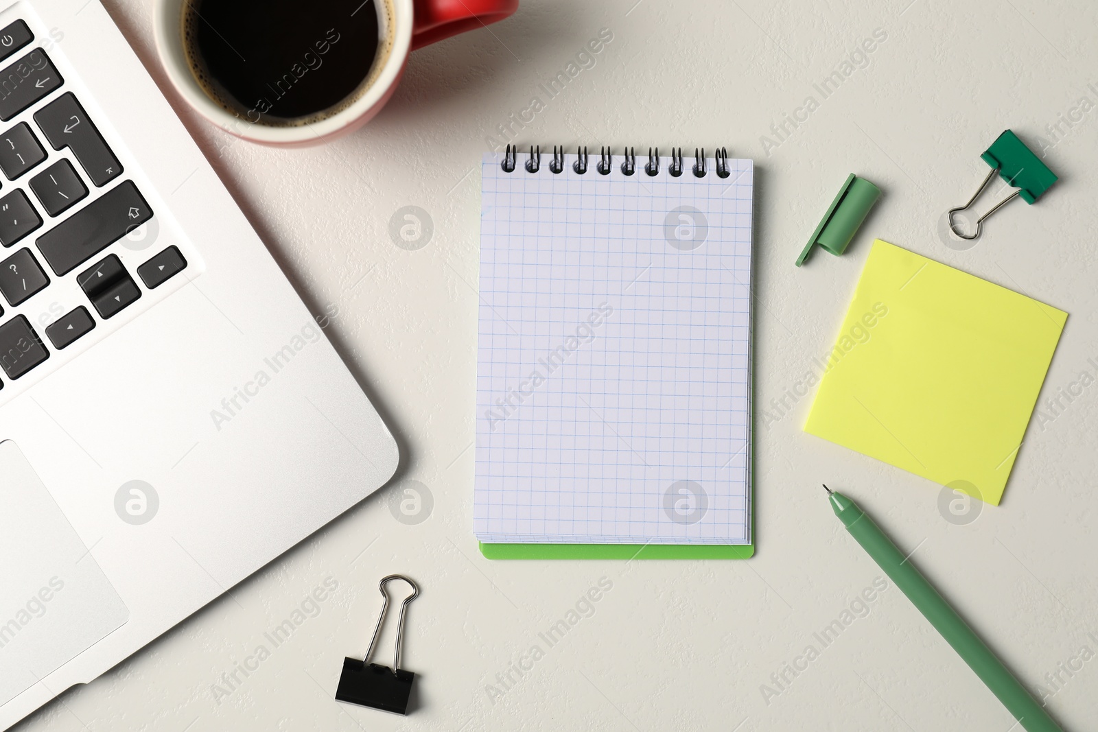 Notebook, sticky note, pen, binder clips, coffee and laptop on white table, flat lay Photo of Notebook, sticky note, pen, binder clips, coffee and laptop on white table, flat lay