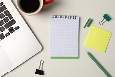 Photo of Notebook, sticky note, pen, binder clips, coffee and laptop on white table, flat lay