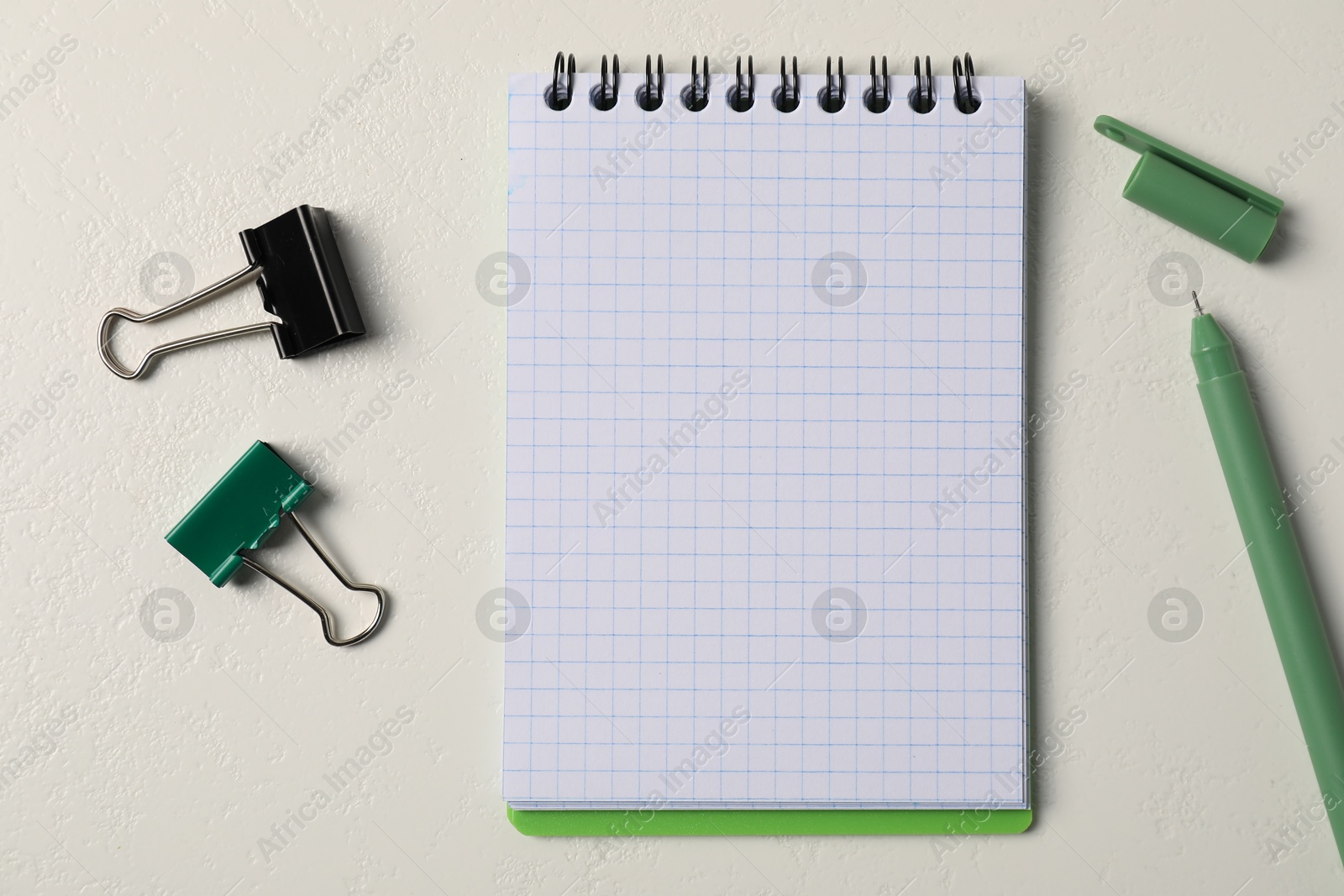 Notebook, pen and binder clips on white table, flat lay Photo of Notebook, pen and binder clips on white table, flat lay
