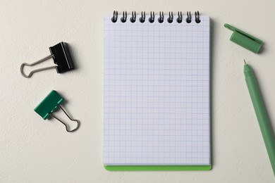 Photo of Notebook, pen and binder clips on white table, flat lay