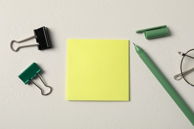 Photo of Sticky note, pen and binder clips on white table, flat lay