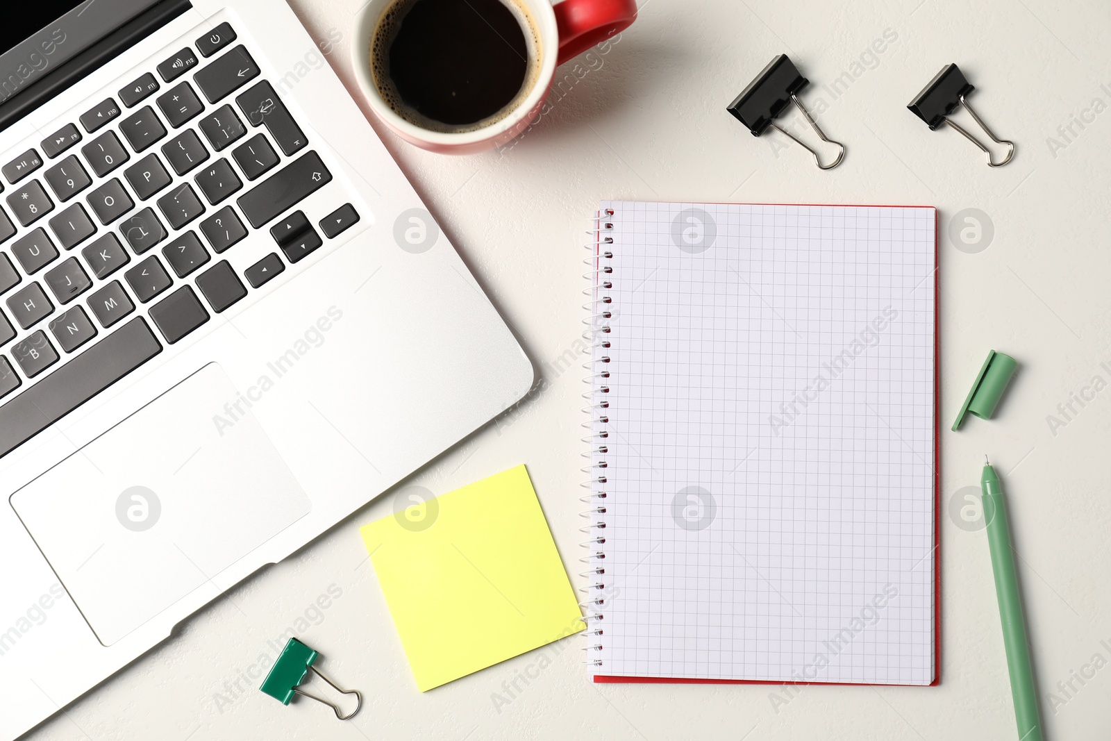 Notebook, sticky note, pen, binder clips, coffee and laptop on white table, flat lay Photo of Notebook, sticky note, pen, binder clips, coffee and laptop on white table, flat lay