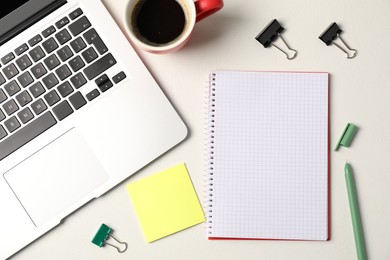 Photo of Notebook, sticky note, pen, binder clips, coffee and laptop on white table, flat lay