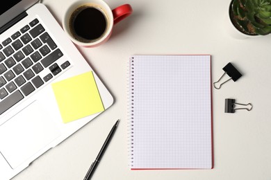 Photo of Notebook, sticky note, pen, binder clips, floral decor, coffee and laptop on white table, flat lay