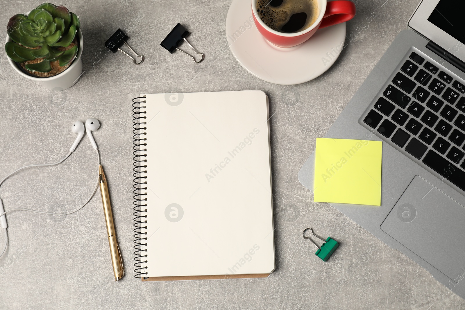 Notebook, pen, sticky note, earphones, coffee, floral decor and laptop on grey table, flat lay Photo of Notebook, pen, sticky note, earphones, coffee, floral decor and laptop on grey table, flat lay