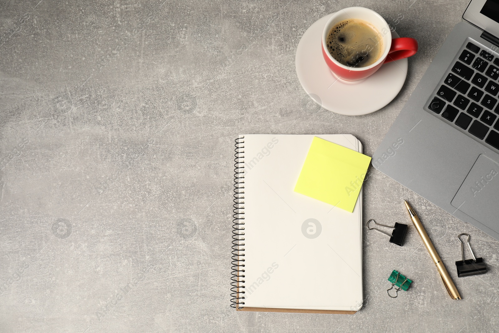 Notebook, pen, sticky note, binder clips, coffee and laptop on grey table, flat lay. Space for text Photo of Notebook, pen, sticky note, binder clips, coffee and laptop on grey table, flat lay. Space for text