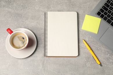 Photo of Notebook, pen, sticky note, coffee and laptop on grey table, flat lay
