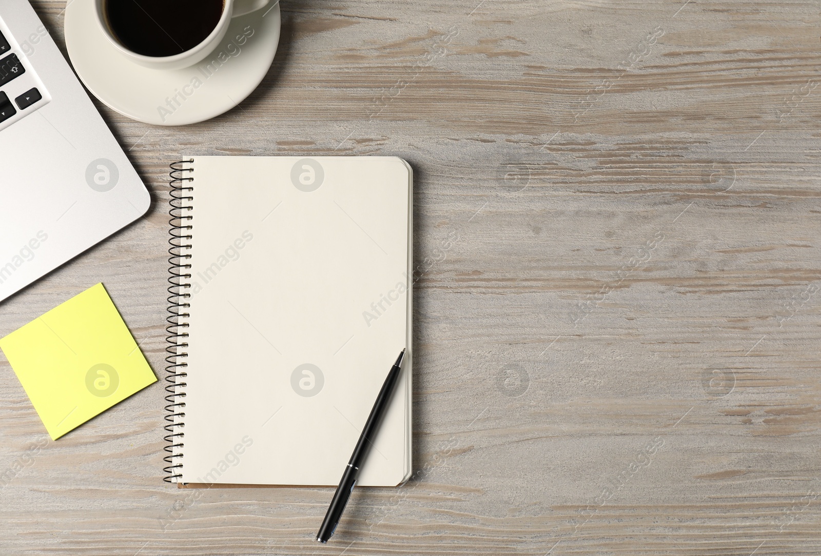 Photo of Notebook, pen, sticky note, coffee and laptop on wooden table, flat lay. Space for text