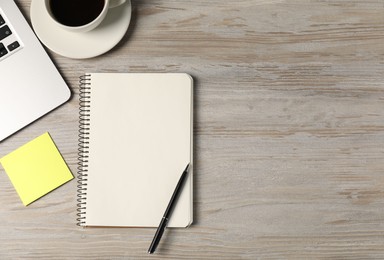 Photo of Notebook, pen, sticky note, coffee and laptop on wooden table, flat lay. Space for text