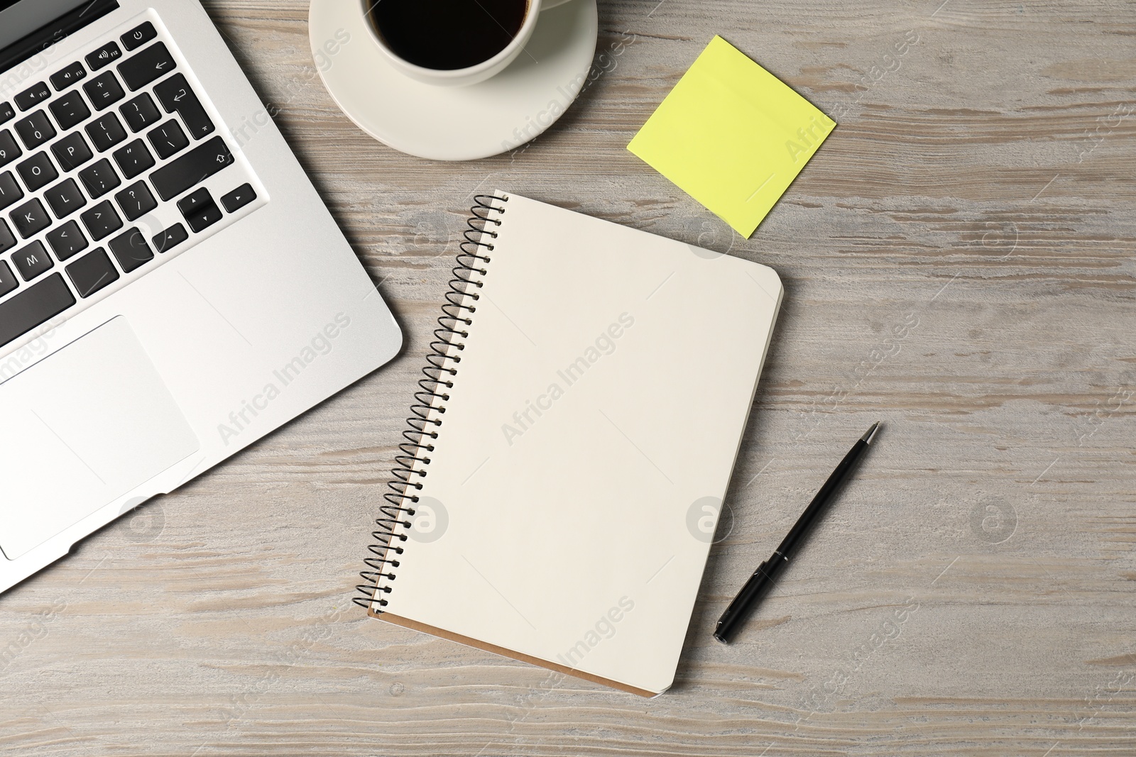 Notebook, pen, sticky note, coffee and laptop on wooden table, flat lay Photo of Notebook, pen, sticky note, coffee and laptop on wooden table, flat lay