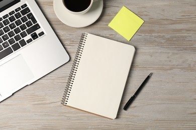 Photo of Notebook, pen, sticky note, coffee and laptop on wooden table, flat lay