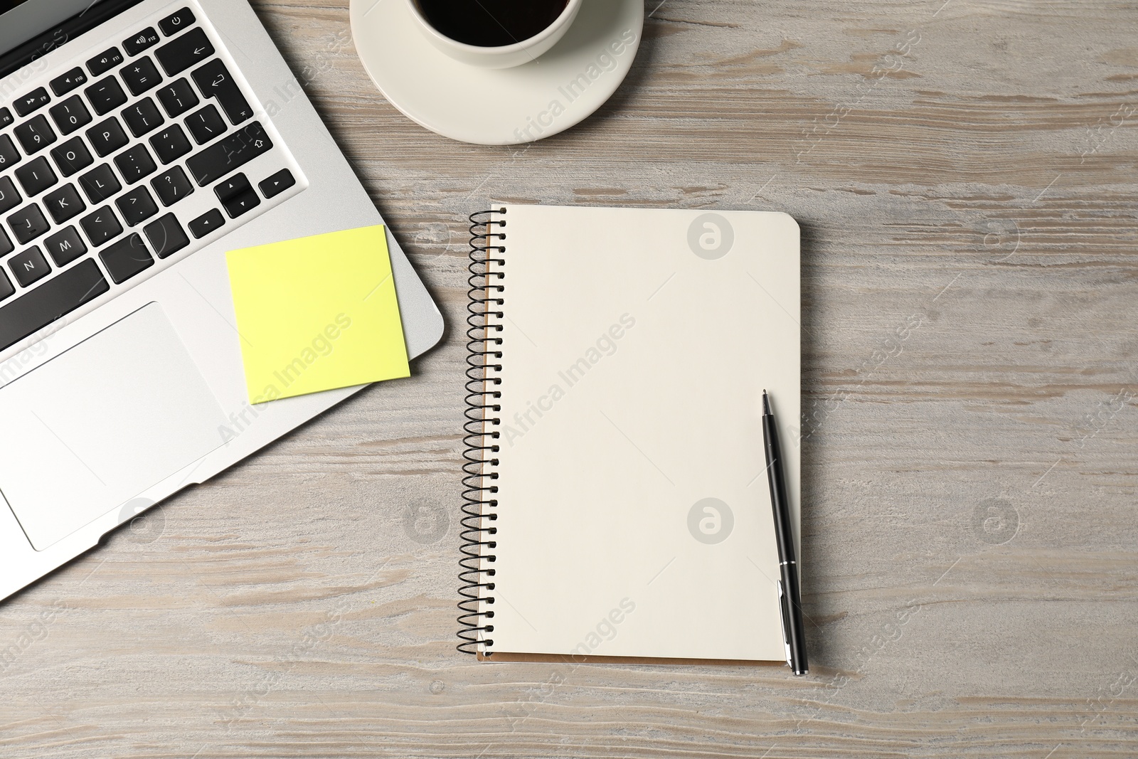 Notebook, pen, sticky note, coffee and laptop on wooden table, flat lay Photo of Notebook, pen, sticky note, coffee and laptop on wooden table, flat lay